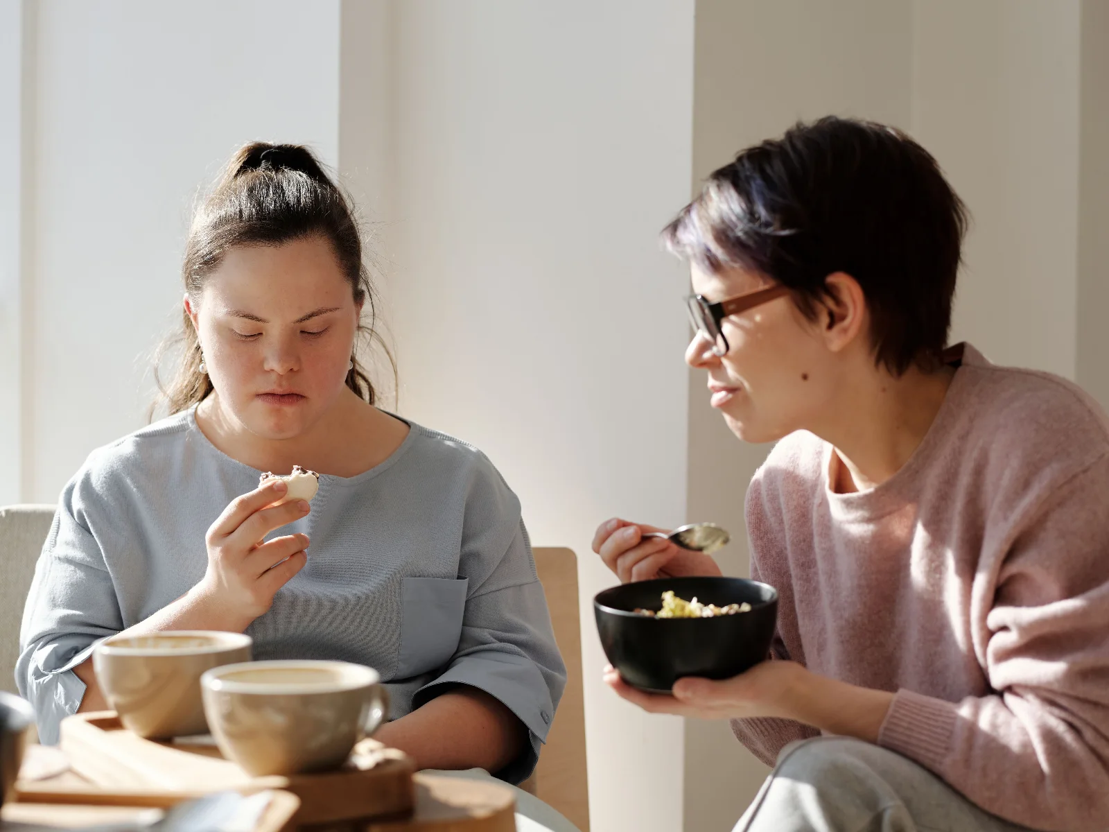 Two women chatting over breakfast at a sunny table