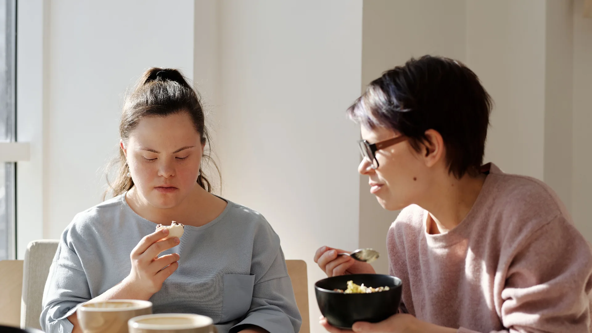 Two women chatting over breakfast at a sunny table
