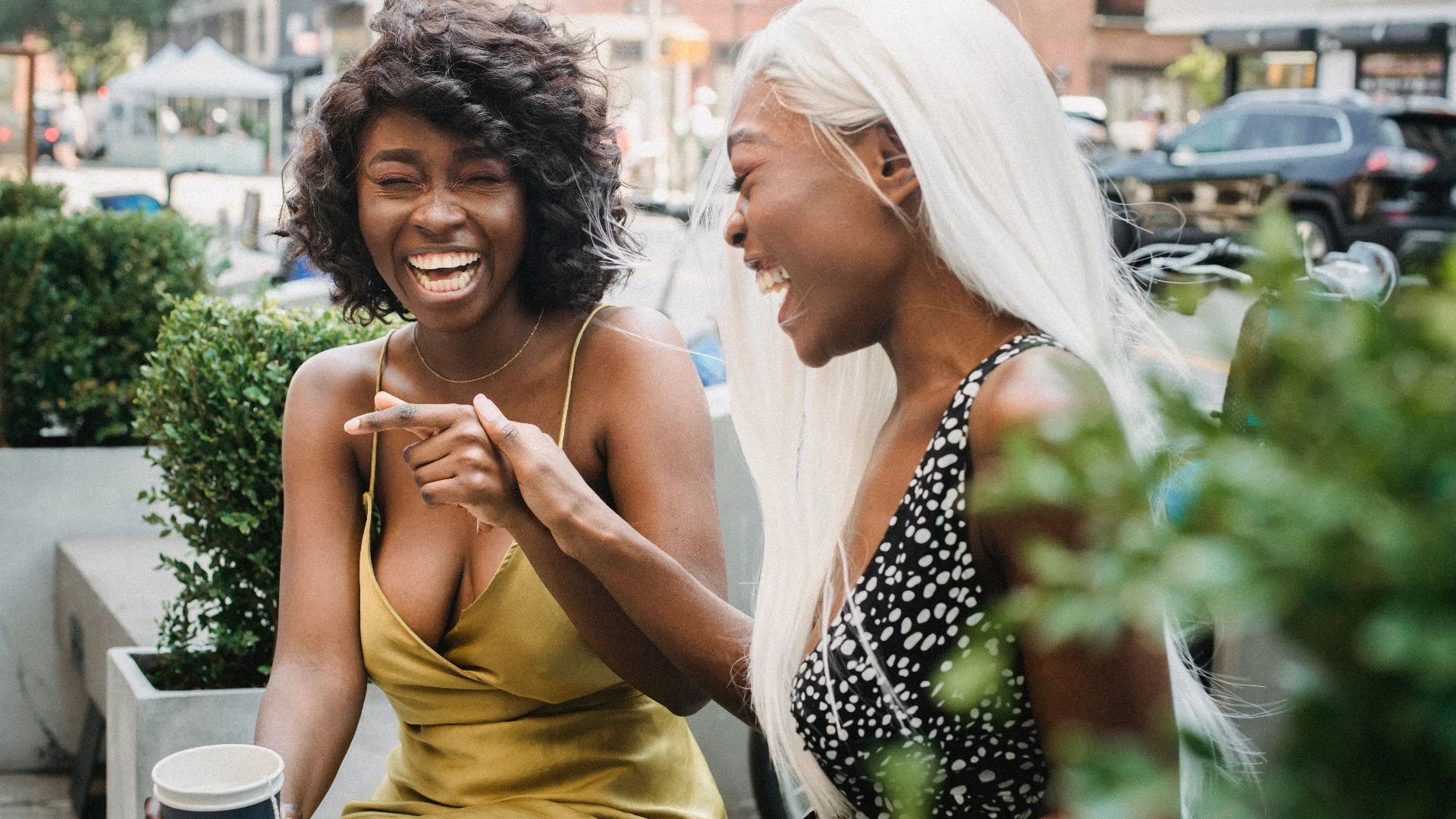 Two women laughing together over coffee at an outdoor café